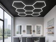 Hexagon HEXO 8-GRID LED-valosarja asennettuna parturin mustaan kattoon muodostaen mehil&auml;iskennomaisen valokokonaisuuden