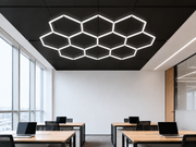 Hexagon HEXO 10-GRID LED-valosarja asennettuna modernin toimiston mustaan kattoon muodostaen hunajakennokuvion