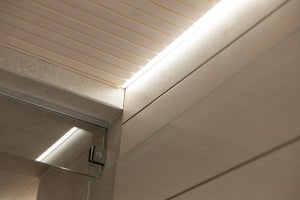 LED-nauha asennettu kattopaneelin ja laattaseinän väliin. Upea, viimeistelty kokonaisuus profiilin avulla. Autamme mielellämme juuri sinun kohteesi valaistuksen suunnittelussa!