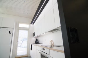 Keittiön yläkaappien alla TEHO LED nauha pinta-asennettavassa valkoisessa profiilissa. Mustassa lipassa sama nauha upotetussa profiilissa.