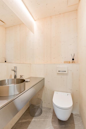 Tyylikäs ja minimalistinen WC-tila, jossa vaalea puupinta ja teräksinen taso luovat modernin ilmeen. Epäsuora LED-nauhvalaistus katon rajassa antaa pehmeän valon ja korostaa tilan luonnollista vaaleutta.