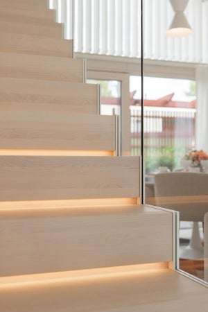 Portaiden väliin upotettu LED-nauha toimii sekä tyylikkäänä valotehosteena että käytännöllisenä kulkuvalona. Lämmin valo korostaa askelmien muotoa ja tuo portaikkoon turvallisuutta ja eleganssia.